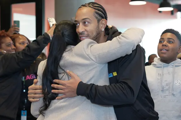 An child holding salad tongs and tossing salad in a purple bowl.
