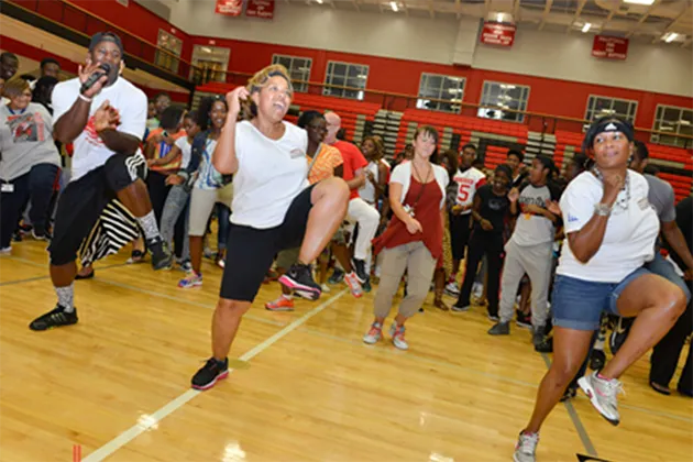 A large group of people wearing athletic clothes and dancing to hip-hop.